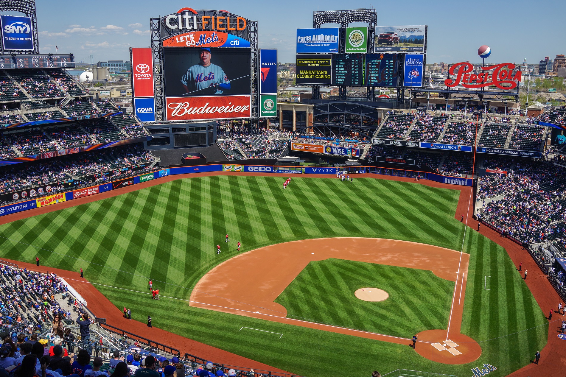 Full view of Citi Field baseball stadium in New York during a Mets game, showing the field, scoreboards, and fans in the stands on a sunny day