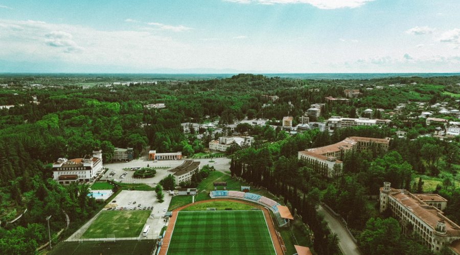 Aerial view of lush greenery and urban landscape in Georgia with a visible sports field and buildings.