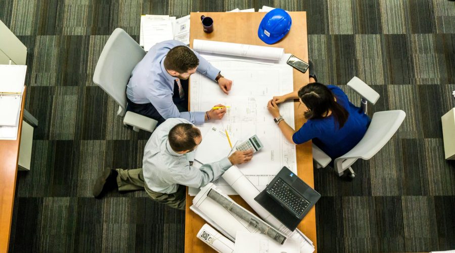 Top view of a team working on construction plans in an office setting.